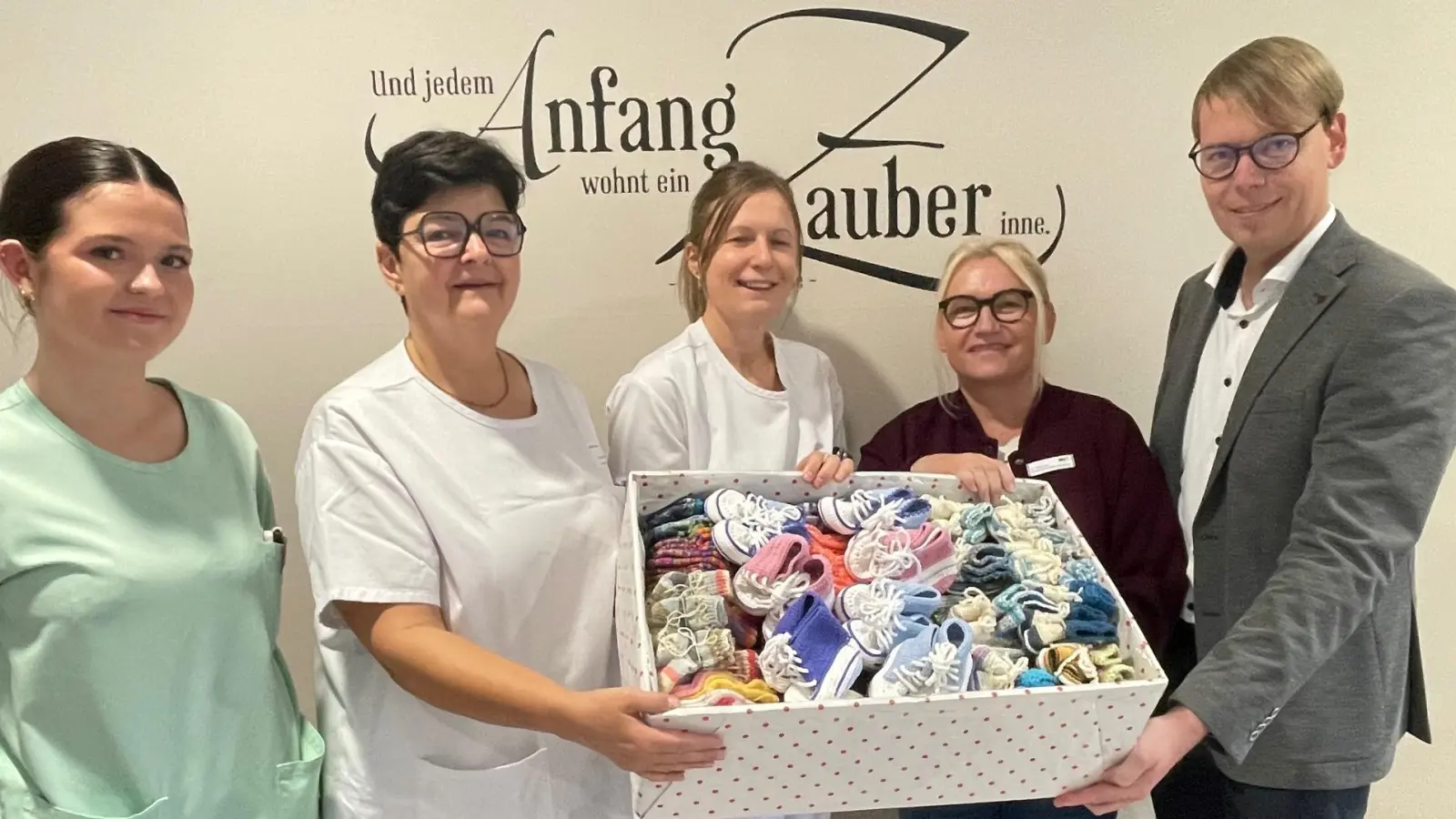 Burgi Zielbauer (Zweite von rechts) überreichte eine Kiste mit 220 Paar gestrickten Söckchen und Schühchen an die Station 32 des Klinikums Weiden. Darüber freuen sich Klinikdirektor Stephan Schumacher (rechts) sowie (von links) Schwesternschülerin Lara Trinkner, stellvertretende Stationsleiterin Jacqueline Kleber und Oberärztin Dr. Ines Erhardt. (Bild: Friedrich Peterhans )