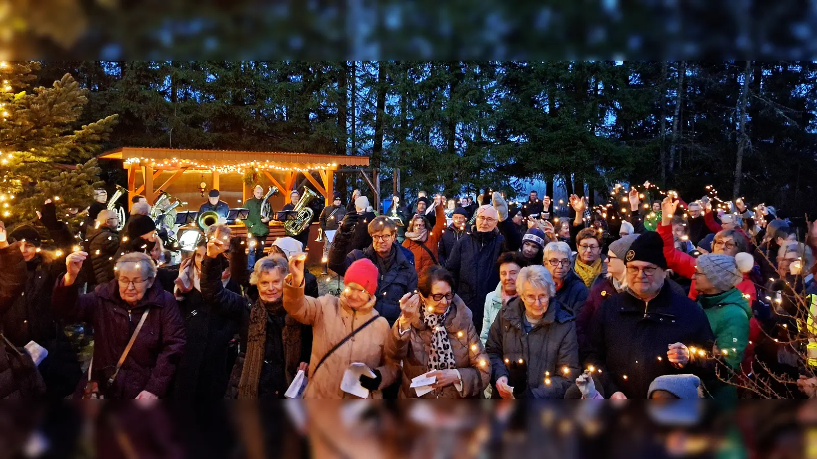 Eine besinnliche und zugleich herzliche Waldweihnachtsfeier richtete der Behinderten- und Vitalsportverein auf seinem festlich mit Lichtern geschmückten Vereinsgrundstück am Schießlweiher aus. Zahlreiche Gäste und Mitglieder feierten vor dem Vereinsheim, halten die Lichterkette in Händen. (Bild: Christopher Birner)