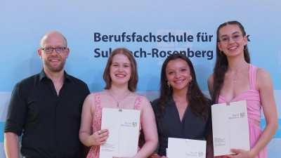 Schulleiter Dominik Lehmeier mit drei von vier der Jahrgangsbesten (von links): Emilia Bolz, Smilla Maier sowie Tabitha Badstübner. Der vierte im Bunde, Marian Metsch, musste sich für die Zeugnisvergabe leider entschuldigen. (Foto: Anna Heidenreich)