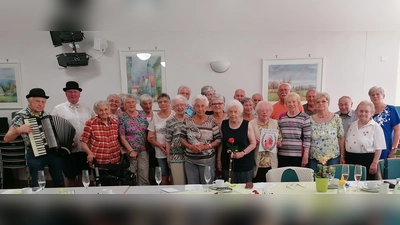 Teilnehmer des Seniorentreffs mit der Jubilarin Marianne Meiler (vorne Mitte mit Rose), Seniorentreffleiterin Elisabeth Schaller (rechts) sowie Musikant Erhard Hirmer und Kolpingvorsitzender Michael Koller als festliche Gratulanten (links). <br><br> (Bild: Michael Koller)