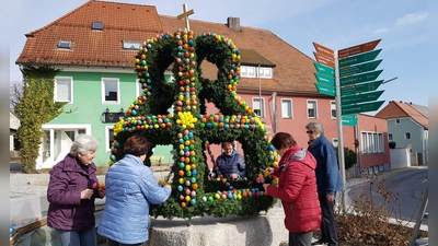 Mitglieder des Frauenbundes haben den Brunnen am Marktplatz mit einer Osterkrone geschmückt. (Bild: Peter Garreiss)