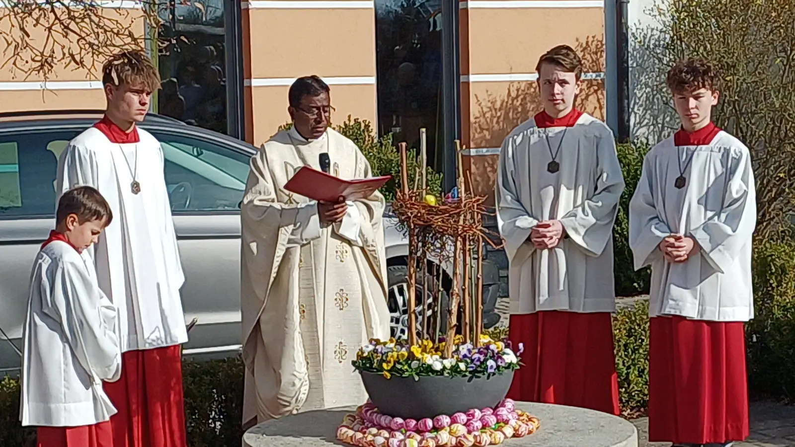 Pfarrer Celestine segnete den österlich geschmückten Quellstein in Wolfring. (Bild: Franz Ziegelmeier)