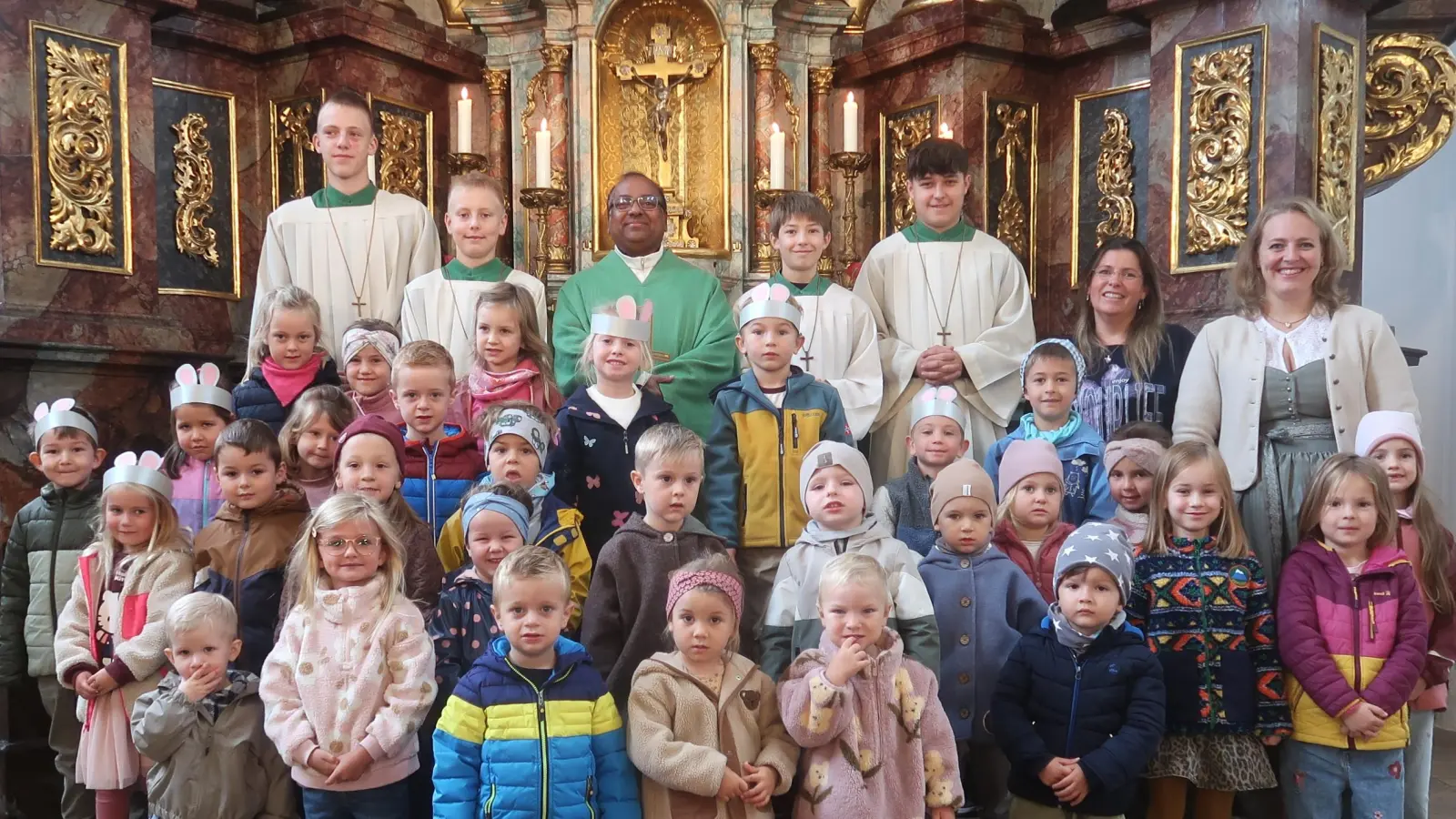 Stadtpfarrer Madanu, seine Ministranten freuen sich mit den Kleinen über das 55-jährige Jubiläum der Kita St. Josef, Vilseck. Leiterin Katharina Kreuzer (ganz rechts) und ihre Stellvertreterin Christina Titz hatten großen Anteil am Gelingen des Festgottesdienstes. (Bild: Rosi Hasenstab)