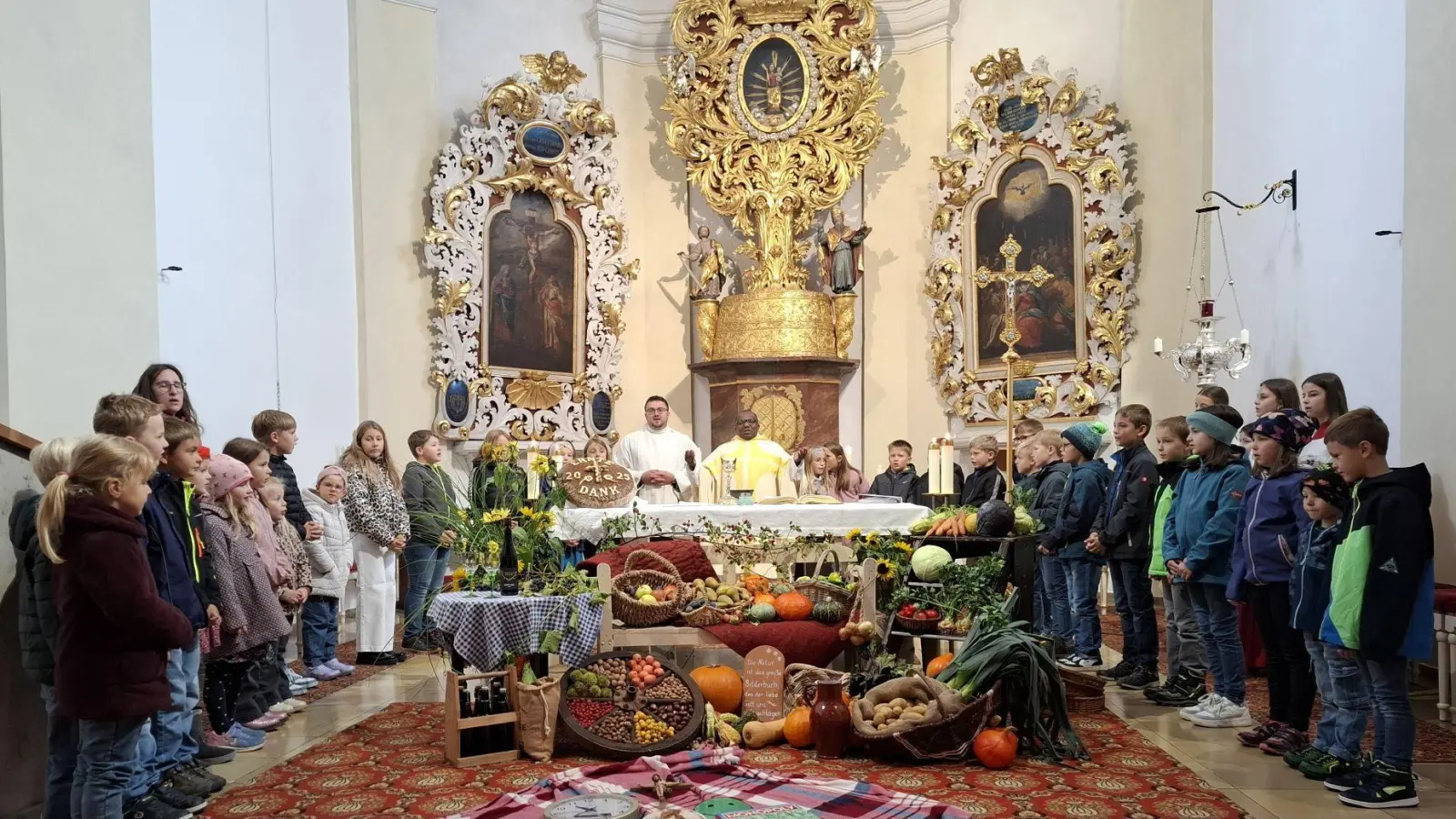Beim Vaterunser versammelten sich die Kinder mit Pfarrvikar Basil und Gemeindereferent Eckert um den reichlich dekorierten Erntedankaltar. (Bild: Karl Ziegler)