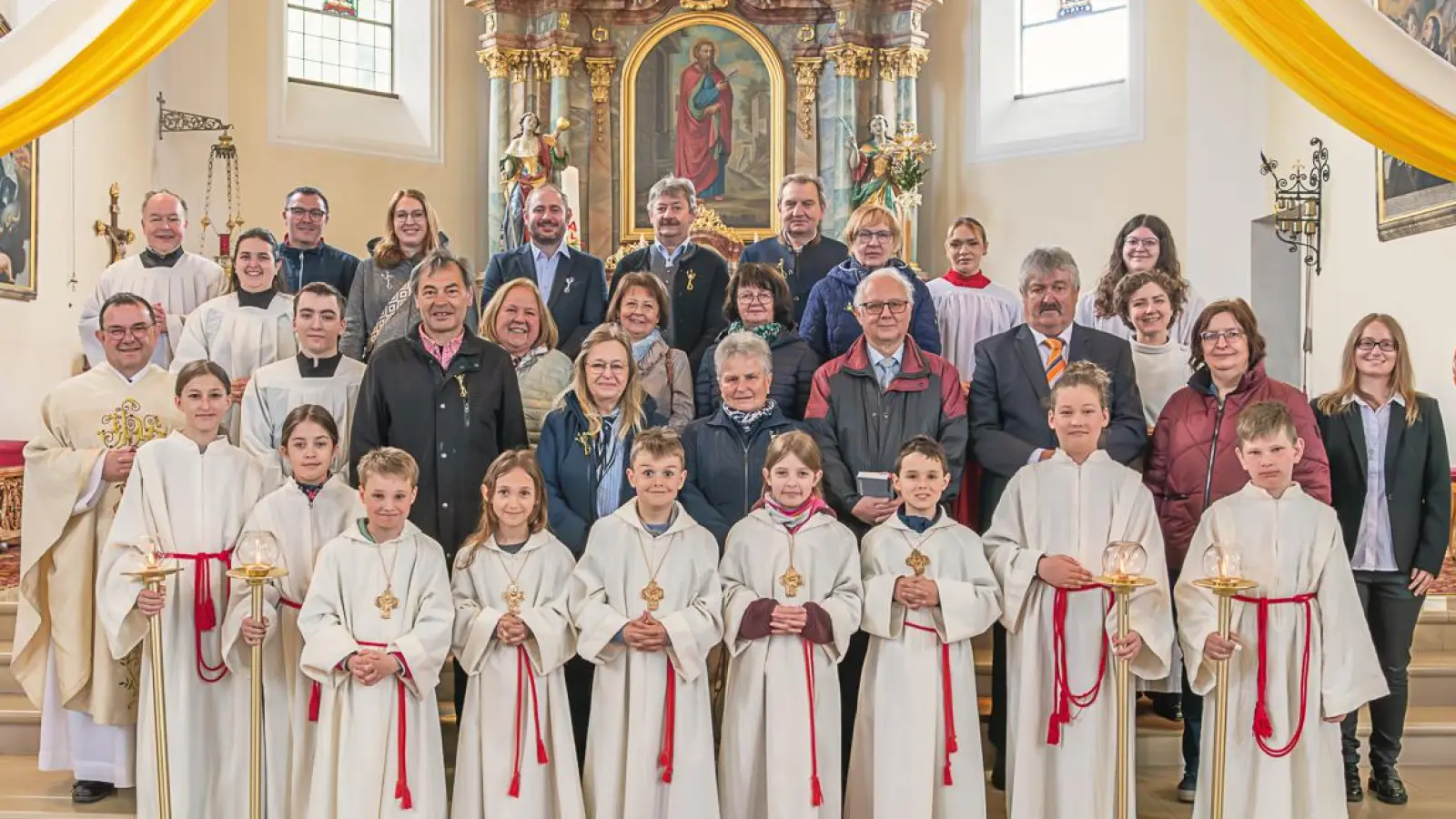 Gruppenfoto der 13 Jubelkommunikanten mit den 5 Erstkommunionkindern, Pfarrer Konrad Amschl, Pastoralreferentin Maria Wagner, Praktikanten Verena Völkl, dem liturgischen Dienst, Pfarrgemeinderatssprecherin Theresia Meindl und Kirchenpfleger Marco Morgado (Bild: ws-fotografie)