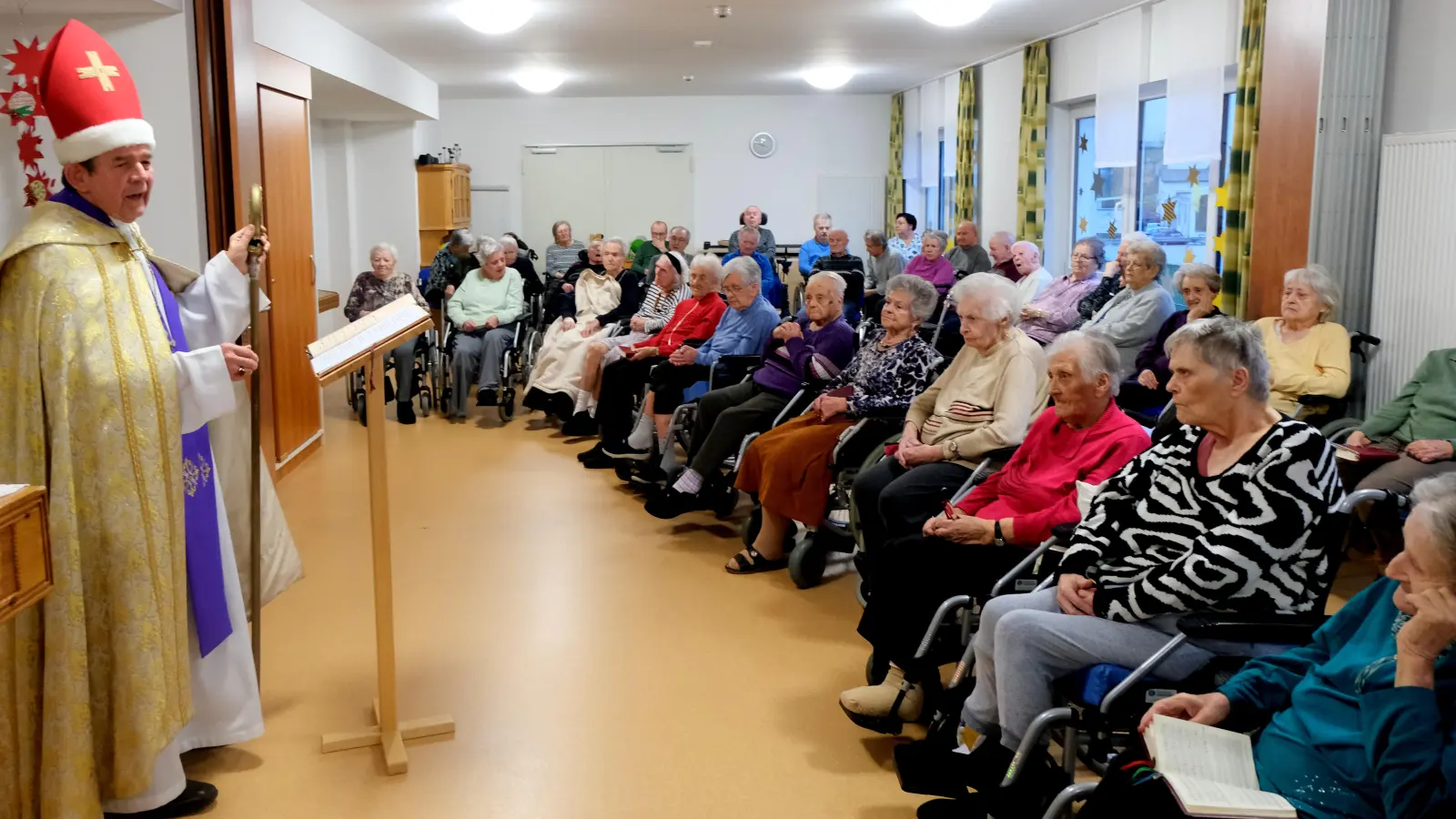 Pfarrer Max Früchtl erschien bei den Bewohnern des Seniorenwohnheimes „Am Reiserwinkel“ im Gewand des Heiligen St. Nikolaus und beschenkt nach dem gemeinsam gefeierten Rorate die Heimbewohner. (Bild: Fred Lehner)