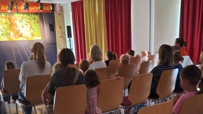 Kinder von der Ferienaktion verfolgen das Geschehen von Kasperl, Gretel und dem Zauberer. (Bild: Romana Wulfänger)