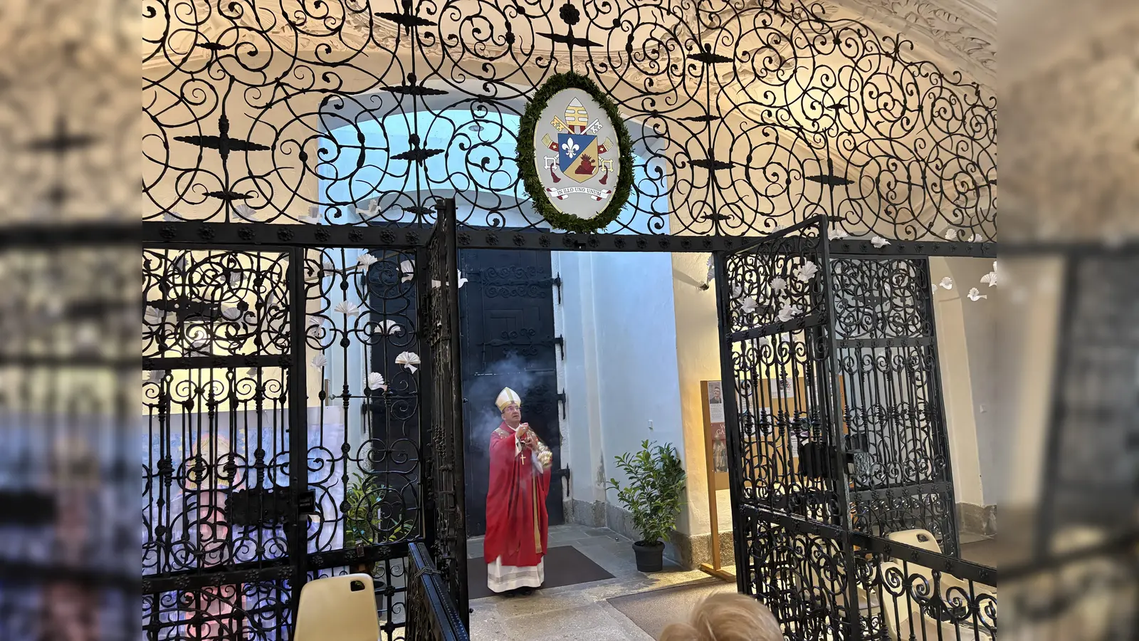 Segnung den neuen Wappen von Papst Leo XIV. durch Erzabt em. Dr. Korbinian Birnbacher OSB. Erstmals sind zwei Wappenschilder sind am Eingangsgitter der Basilika angebracht sind, so das das Wappen auch schon beim Betreten der Basilika gesehen werden kann. (Bild: Markus Scharnagl)
