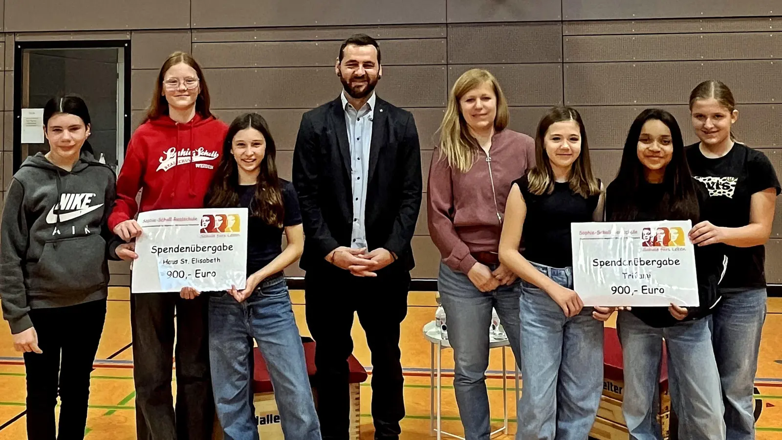  Schülerinnen der 6. Klassen überreichen zwei symbolische Spendenschecks – für strahlende Gesichter auf beiden Seiten. 4. von links Peter Wasel, 5. von links Verena Urban und die Mädchen mit den meisten geschwommenen Bahnen.  (Bild: Martina Brunner)