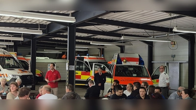 Kreisgeschäftsführer Sebastian Schaller und Kreisvorsitzender Gerd Geismann bei ihren Grußworten, daneben Alexander Bollow (Bereitschaftsleiter Sulzbach-Rosenberg), im Hintergrund ein Teil der geweihten Fahrzeuge. (Bild: Tobias Schmidt)