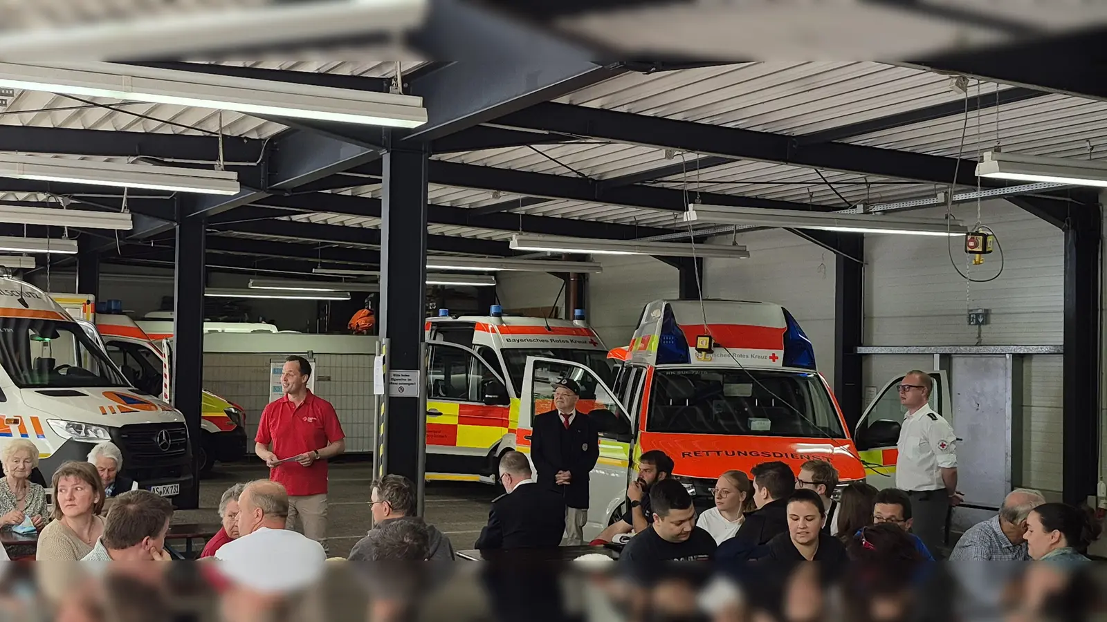 Kreisgeschäftsführer Sebastian Schaller und Kreisvorsitzender Gerd Geismann bei ihren Grußworten, daneben Alexander Bollow (Bereitschaftsleiter Sulzbach-Rosenberg), im Hintergrund ein Teil der geweihten Fahrzeuge. (Bild: Tobias Schmidt)
