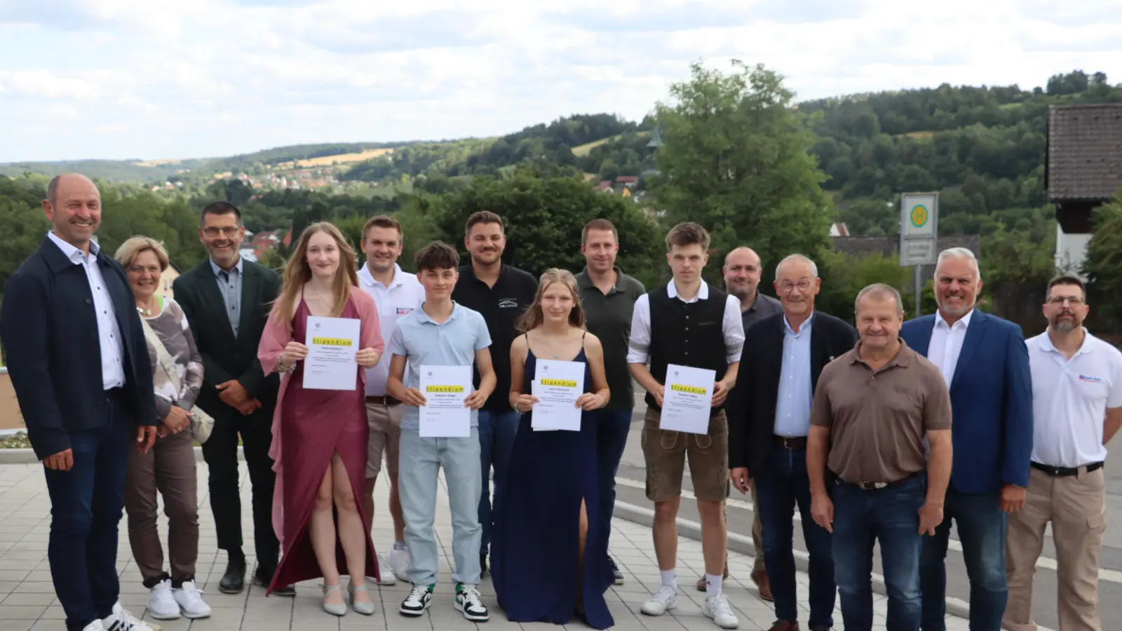 Die vier Jahrgangsbesten der Mittelschule Ensdorf, Alina Reichert (mit Urkunde, v.l.), Andreas Singer, Lucy Fuhrmann und Bastian Völkel mit Ensdorfs BGM Hans Ram (l.), Riedens BGM Erwin Geitner (4.v.r.), Schmidmühlens Drittem BGM Thomas Wagner (2.v.r.) und den Sponsoren. (Bild: Michael Rabenhofer)