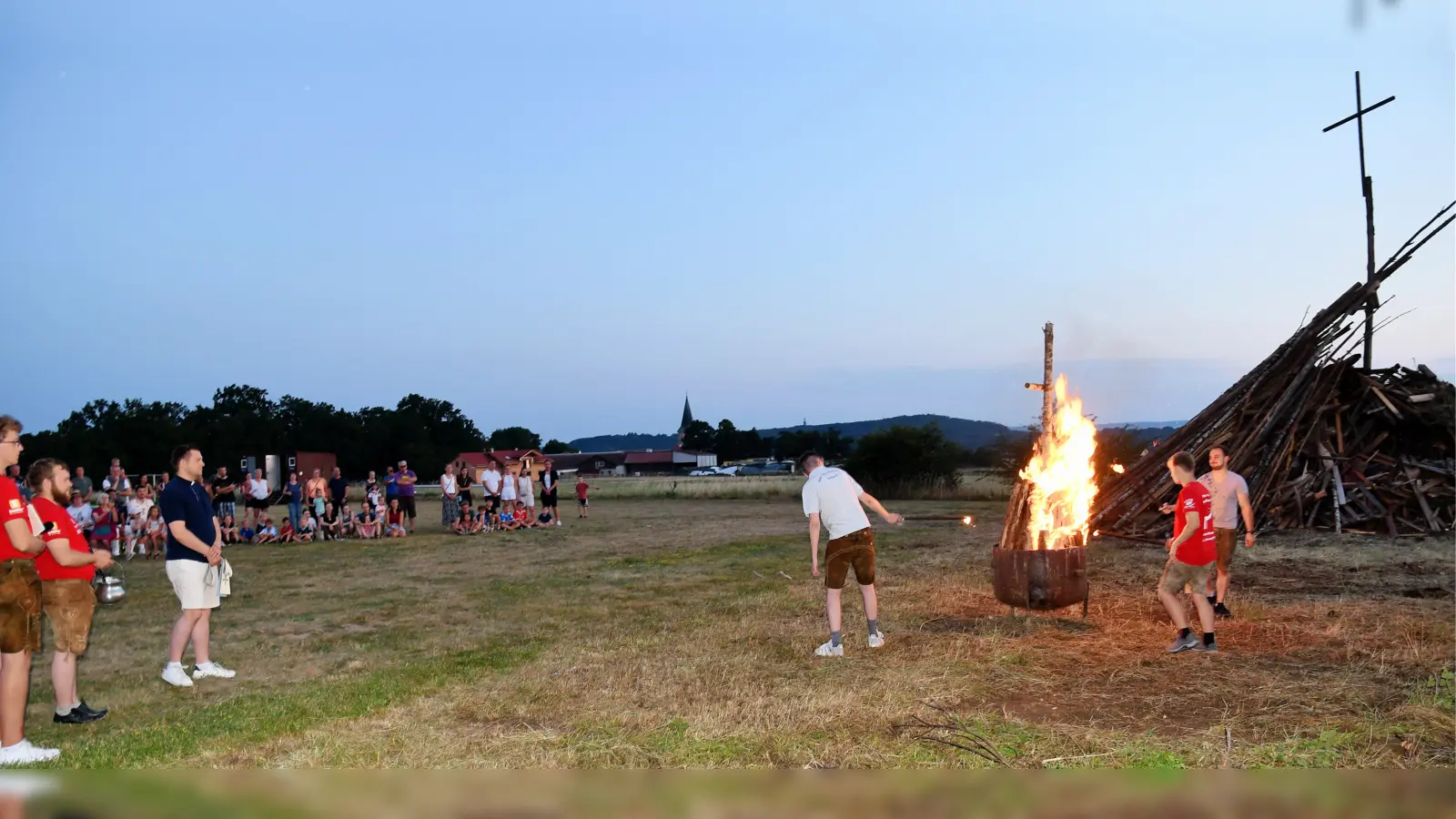 Bei Einbruch der Dunkellheit oblag es Kaplan Marvin Schwedler nach einer kurzen Andacht das Johannisfeuer in geschmälerter Ausführung zu segnen. Der ursprünglich hierfür vorgesehene große Holzstoß durfte aufgrund der extremen Trockenheit nicht entzündet werden. (Bild: Alfred Schorner)