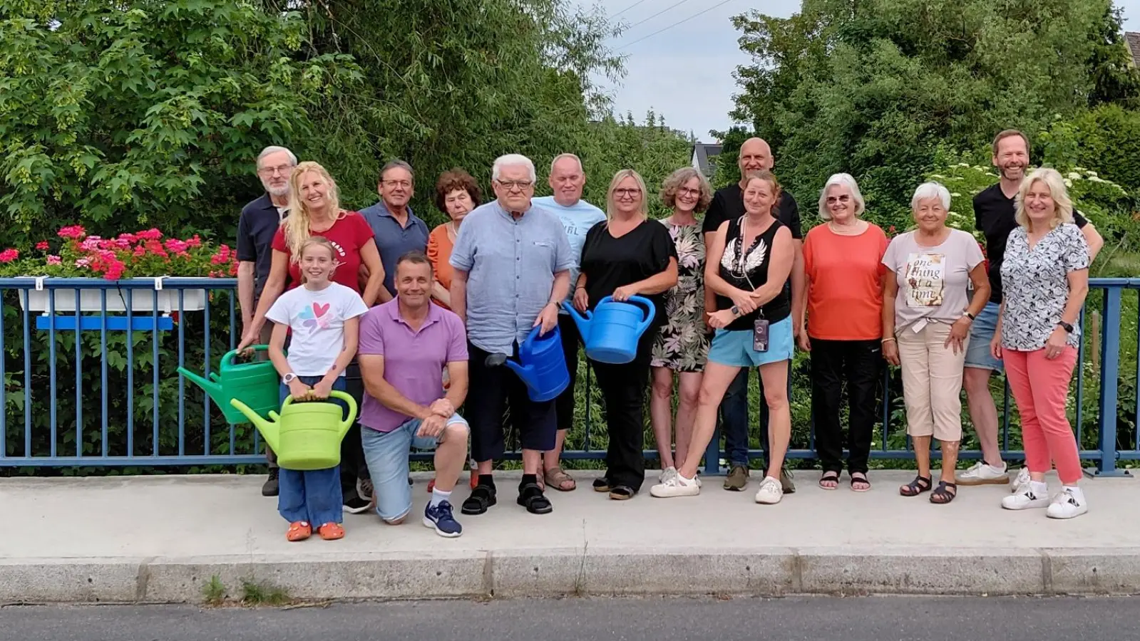 Insgesamt acht Blumenkästen wurden an der Mühlbachbrücke wieder angebracht. Auf dem Bild ein Teil der Anwohner, die den Blumenschmuck pflegen. Uwe Bergmann (vorne, Zweiter von links) und Harald Kausler (Zweiter von rechts) hatten das Ganze wieder organisiert. Zweite Bürgermeisterin Elisabeth Kraus (rechts) lud im Namen der Stadt zu einem kleinen Umtrunk ein. (Bild: David Bergmann)