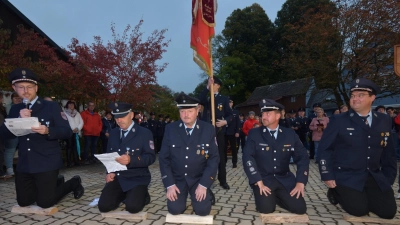 ie Vorstände und die Kommandanten der Feuerwehr Ebnath knieten auf Holzscheiteln nieder, um die Feuerwehr Pullenreuth feierlich um die Patenschaft zu bitten. (Bild: Josef Söllner)