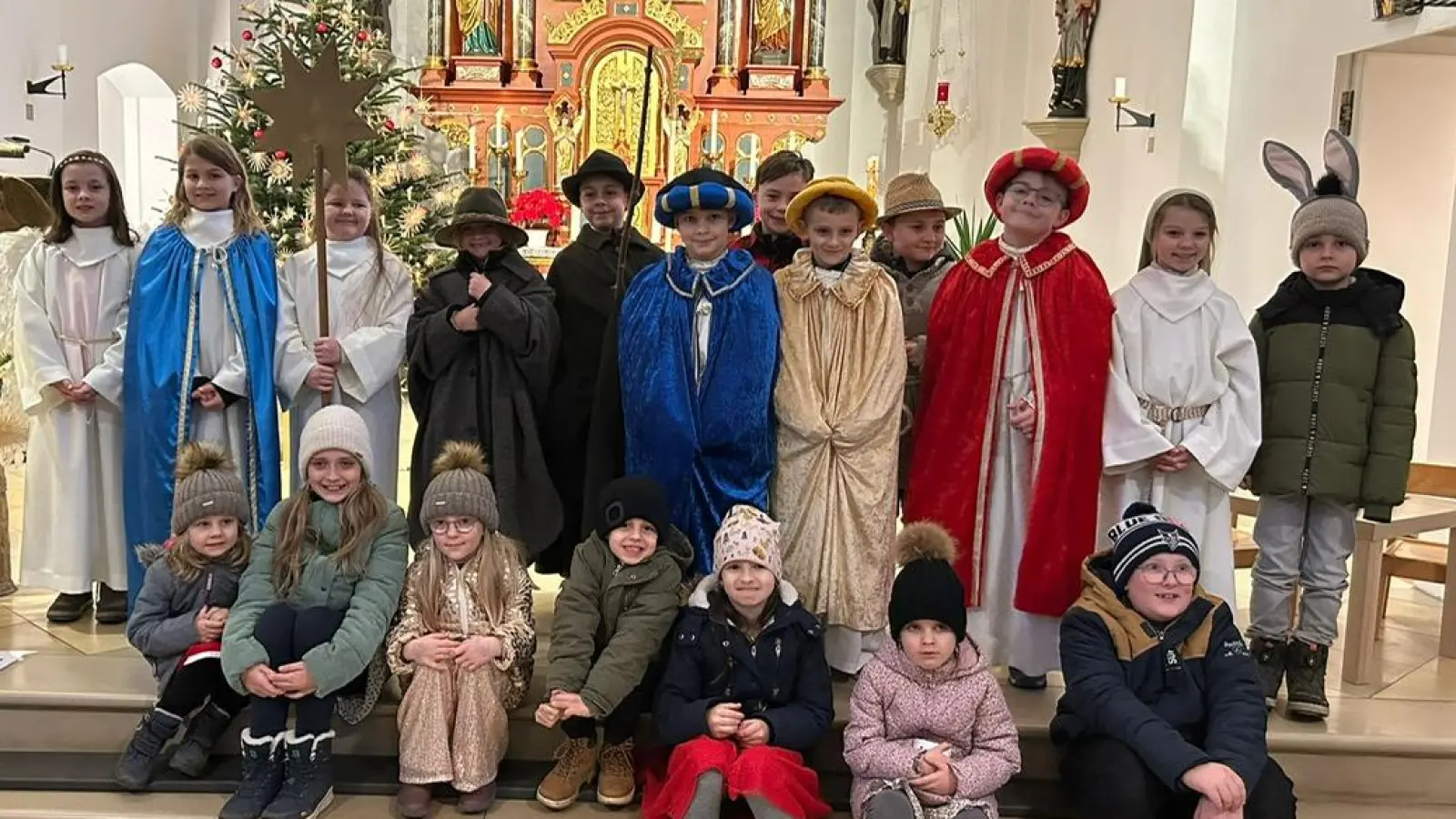  Die Kommunionkinder in Theaterkostümen führten das Krippenspiel auf und der Kinderchor (sitzend) wurde von Veronika Hirmer auf der Gitarre begleitet. (Bild: Katrin Baier)