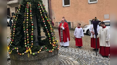 Pfarrer Alfons Forster mit den Ministranten am Osterbrunnen bei der Segnung der Palmbüschel, deren Erlös nach Indien geht. (Bild: Maria Winter)
