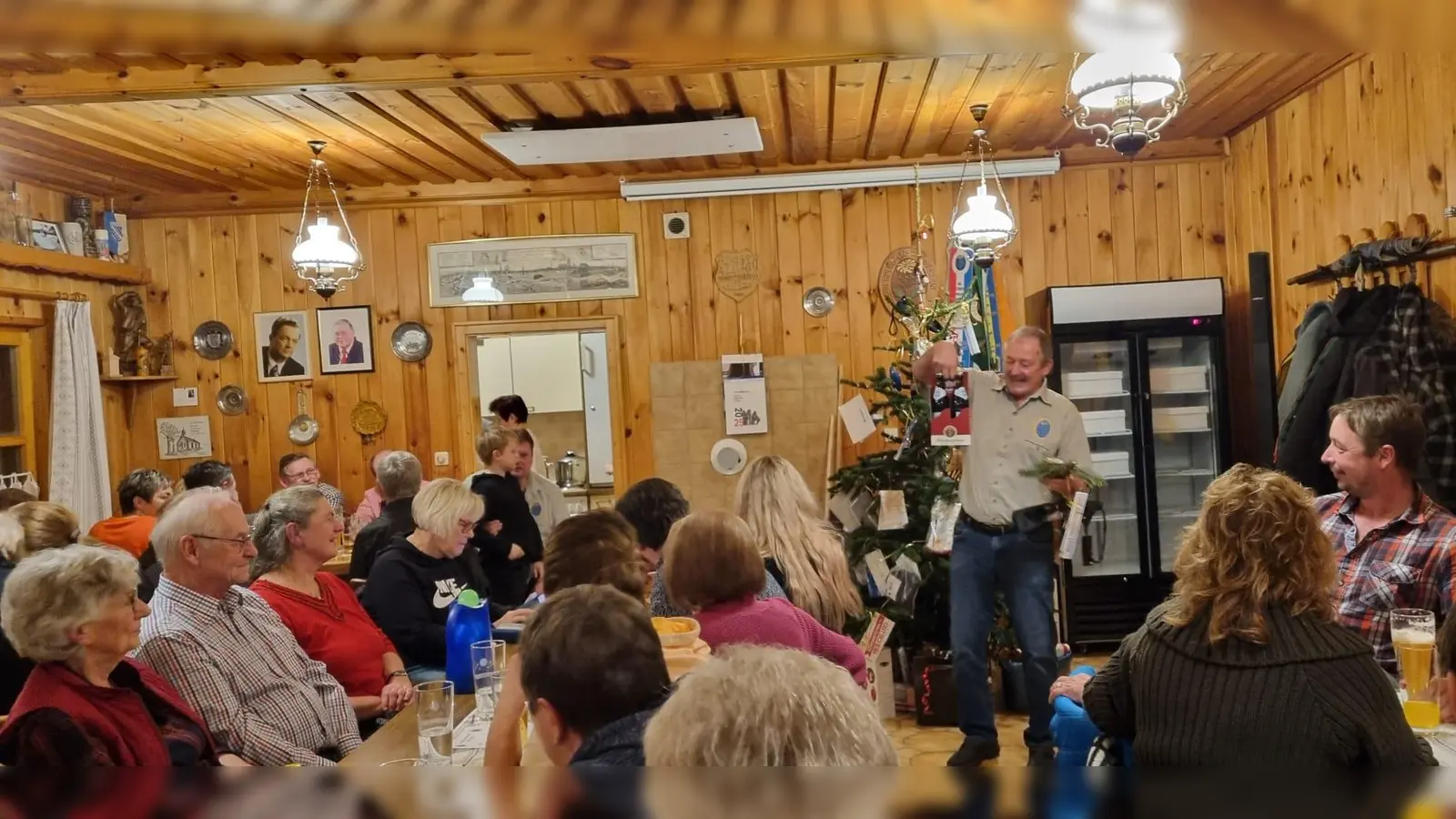 Erster Vorsitzender Josef Frischmann (stehend) stellt die gesammelten Preise den Gästen zur Versteigerung vor. (Bild: Dominik Brenner)