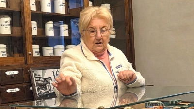 Expertin in ihrem Element: Helma Koch hinter dem historischen Tresen der Alten Hof-Apotheke. Als Kennerin der ‚alten Schule‘ erklärte sie den KulTourAS-Gästen, wie Medikamente früher von Hand gewogen und gerührt wurden. (Bild: Walter Heldrich)