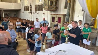 Mesner Johannes Zeindl (mit Kreuz in der Hand) zeigte den Ministranten und ihren Eltern auf anschauliche Weise die beiden Riedener Kirchen und ihre besonderen Schätze. (Bild: Marion Hollweck)