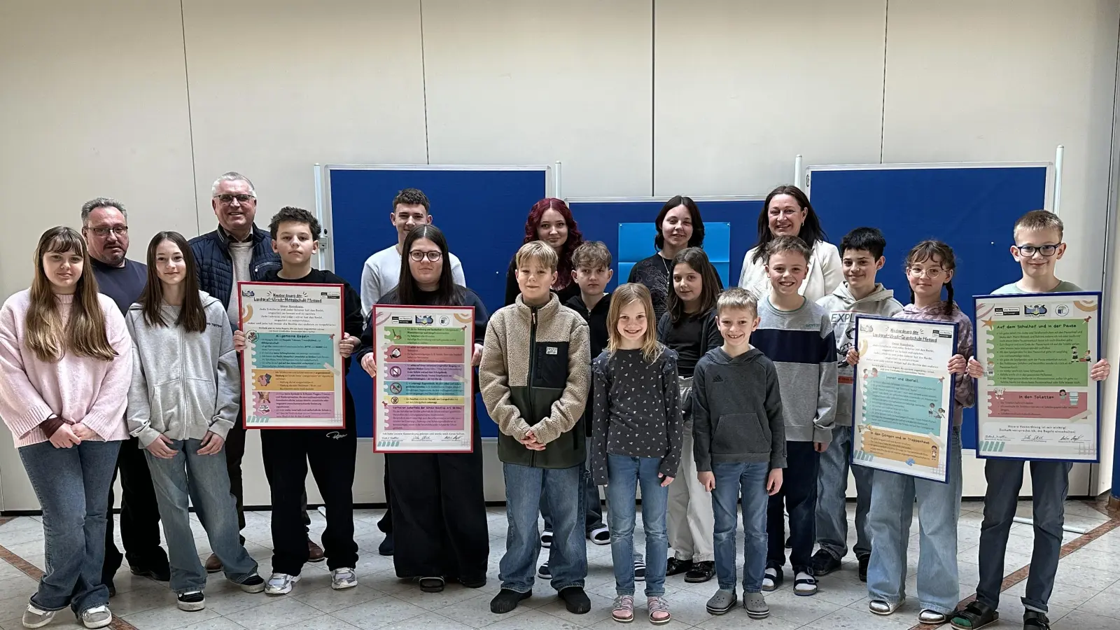 Schülerinnen und Schüler, Rektorin Silke Schmid, Bürgermeister Richard Tischler und Hausmeister Markus Muntanjohl mit den neu ausgearbeiteten Hausordnungen der Grund- und Mittelschule Pfreimd. (Bild: Jasmin Ulrich)