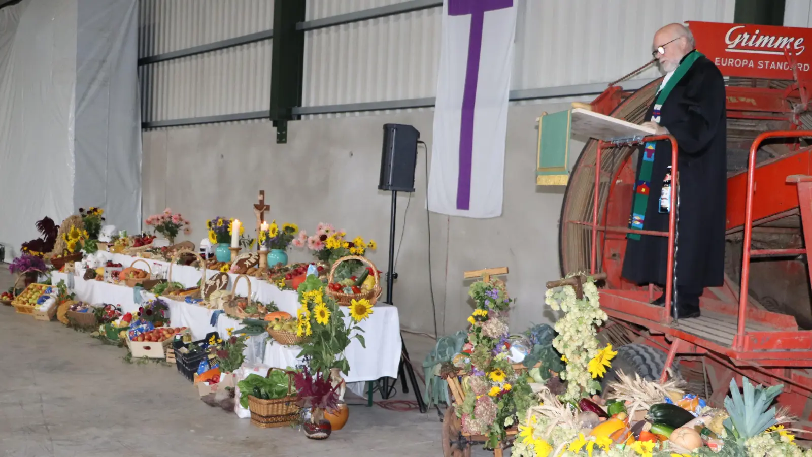 Auf einem Kartoffelvollernter aus den 70iger Jahren der Kleinstbauern aus Freihung predigte Pfarrer Ahnert in den beiden Gottesdienst in der landwirtschaftlichen Maschinenhalle in Wegscheid zum Erntedankfest. (Bild: Rudi Gruber)