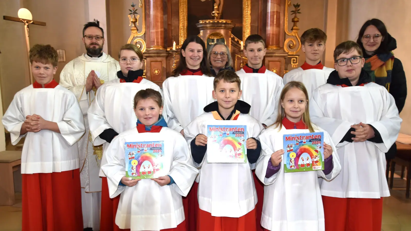 die drei neuen „Minis” der kath. Pfarrei Illschwang (von links/vorne) Zillie Lang, Gabriel Pesold und Sophia Weiß (mit dem Ministrantenkalender), den Ministranten, die bei der Messe im Einsatz waren, sowie Pfarrer Johannes Arweck (2. von links), pastorale Mitarbeiterin Carolin Streller (rechts) und Mesnerin Elisabeth Dürgner (Mitte). (Bild: Norbert Weis)
