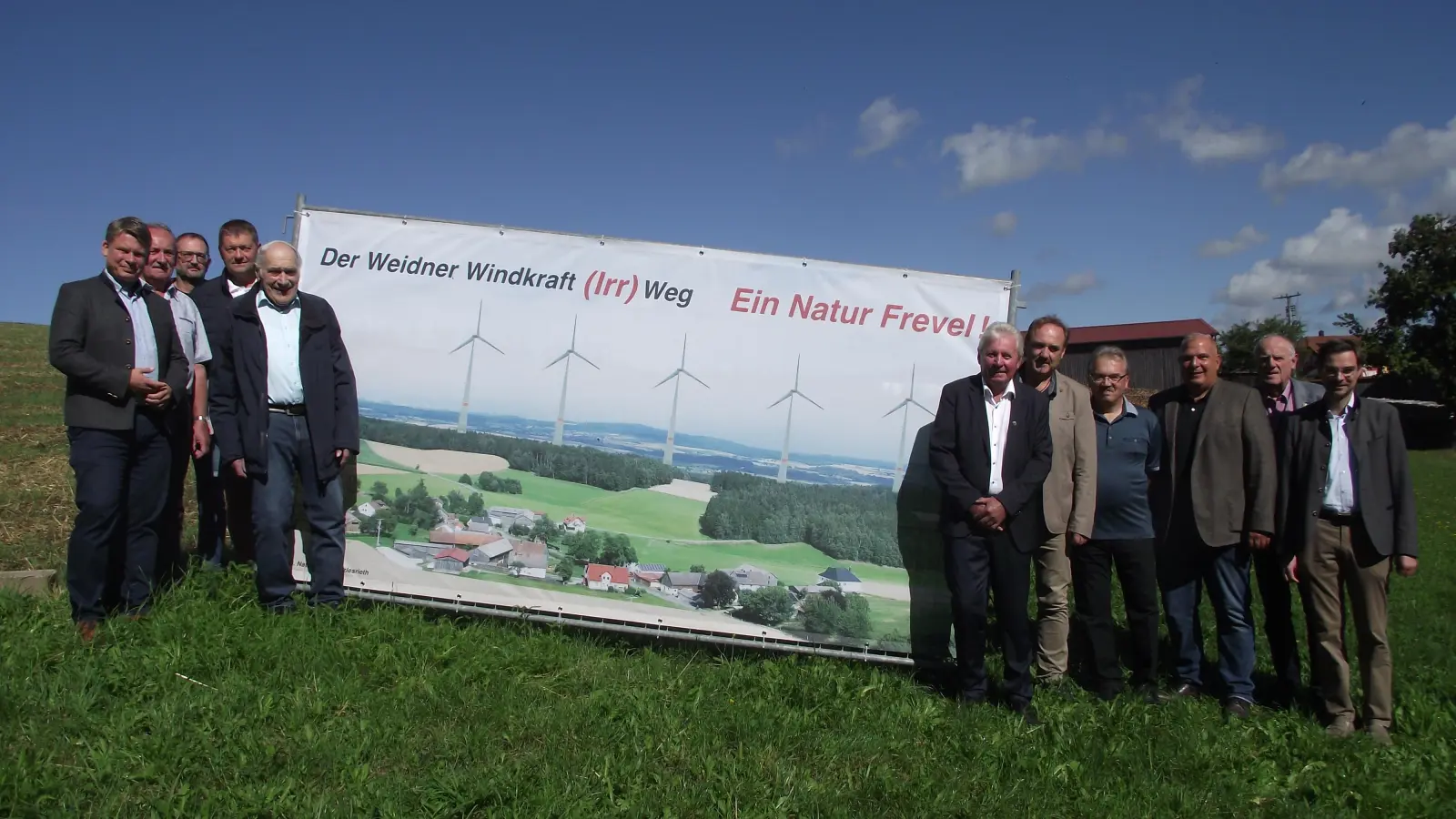 Zusammen mit den Ortsbewohnern von Matzlesrieth, nutze Hans Balk (5. Von links) im Namen der „Interessengemeinschaft Naturerhalt“ die Gelegenheit, die CSU Stadtratsprominenz bei deren Besuch in Matzlesrieth vor dem aufgestellten riesigem Banner mit den geplanten Windrädern, sie zu einer Informationsveranstaltung zu dem aufgedruckten Motto einzuladen.  (Bild: Robert Ronke)