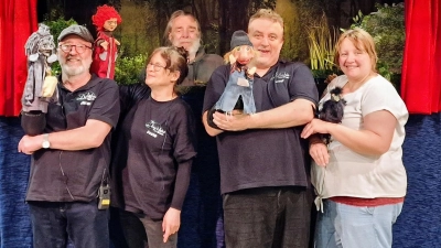 Das FiDo-Team der Dorfbühne Waidhaus präsentiert stolz ihre handgefertigten Figuren vor der fantasievoll gestalteten Bühne – ein kreatives Ensemble voller Herz und Leidenschaft. (Bild: Josef Kleber)