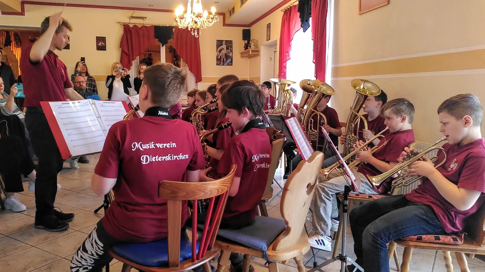 Jürgen Lößl dirigiert die Bläserklasse souverän durch ihr Repertoire. Die Fans der Nachwuchsmusiker filmen.  (Bild: Jasmin Brandl)