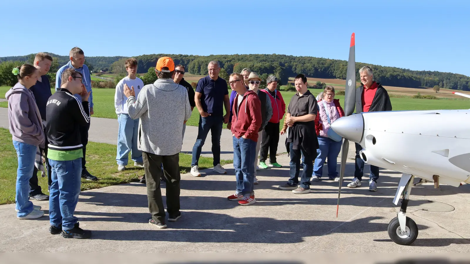 Peter Ostermann von der Luftsportgruppe (oranges Käppi) begrüßte die Gäste und Vertreter der Vereine und erklärte ansxhließend die Flugzeuge, die in Fichtelbrunn stationiert sind. (Bild: Heidi Franitza)