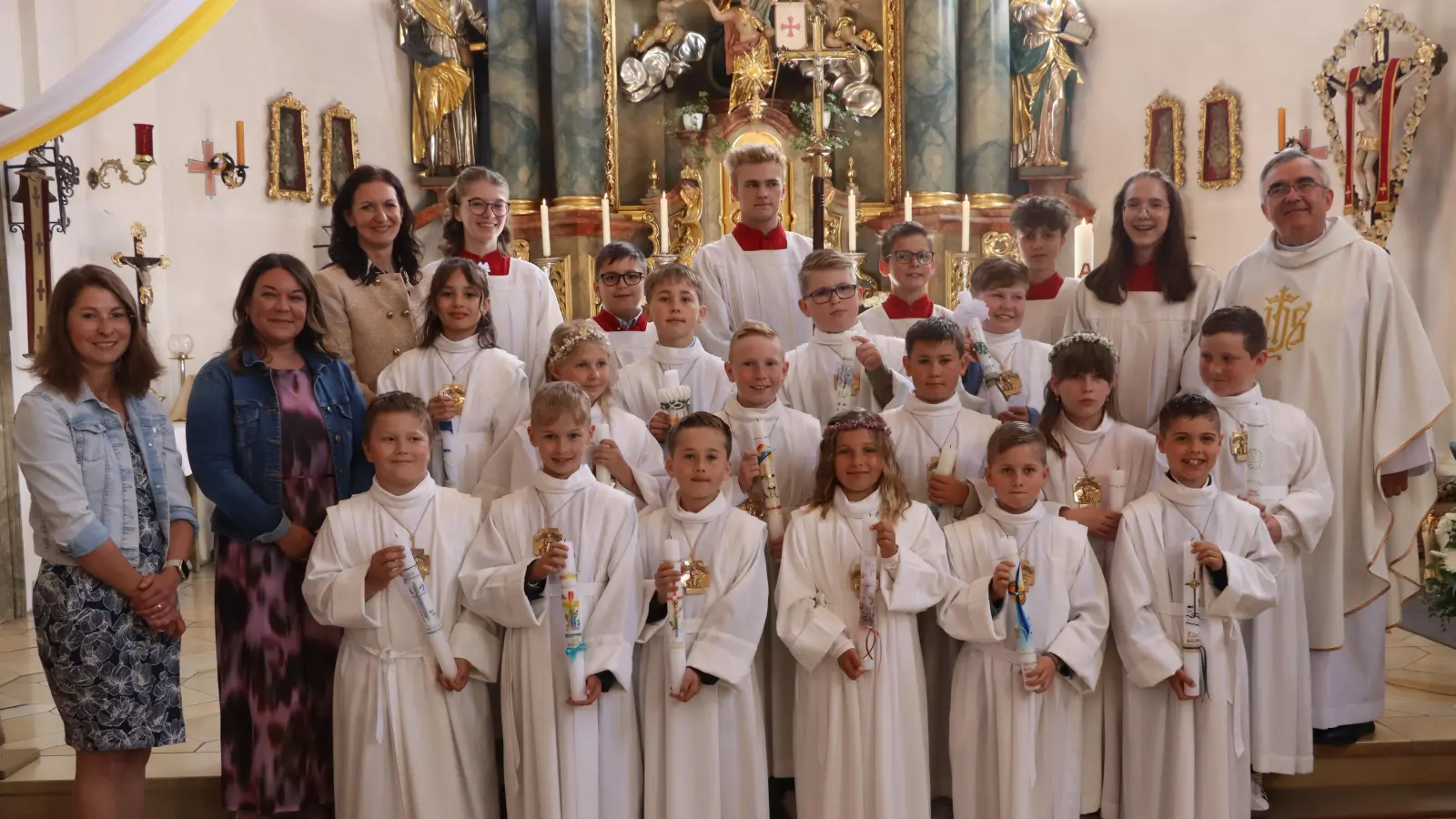 Die Erstkommunionkinder 2026 der Pfarreien Rieden und Vilshofen mit Pfarrer Slawomir Niemczewski (r.) und den Schullehrerinen Jana Neumann (v.l.) und Anna Liebhäuser, Rektorin Christine Kölbl sowie die Ministranten. (Bild: Michael Rabenhofer)