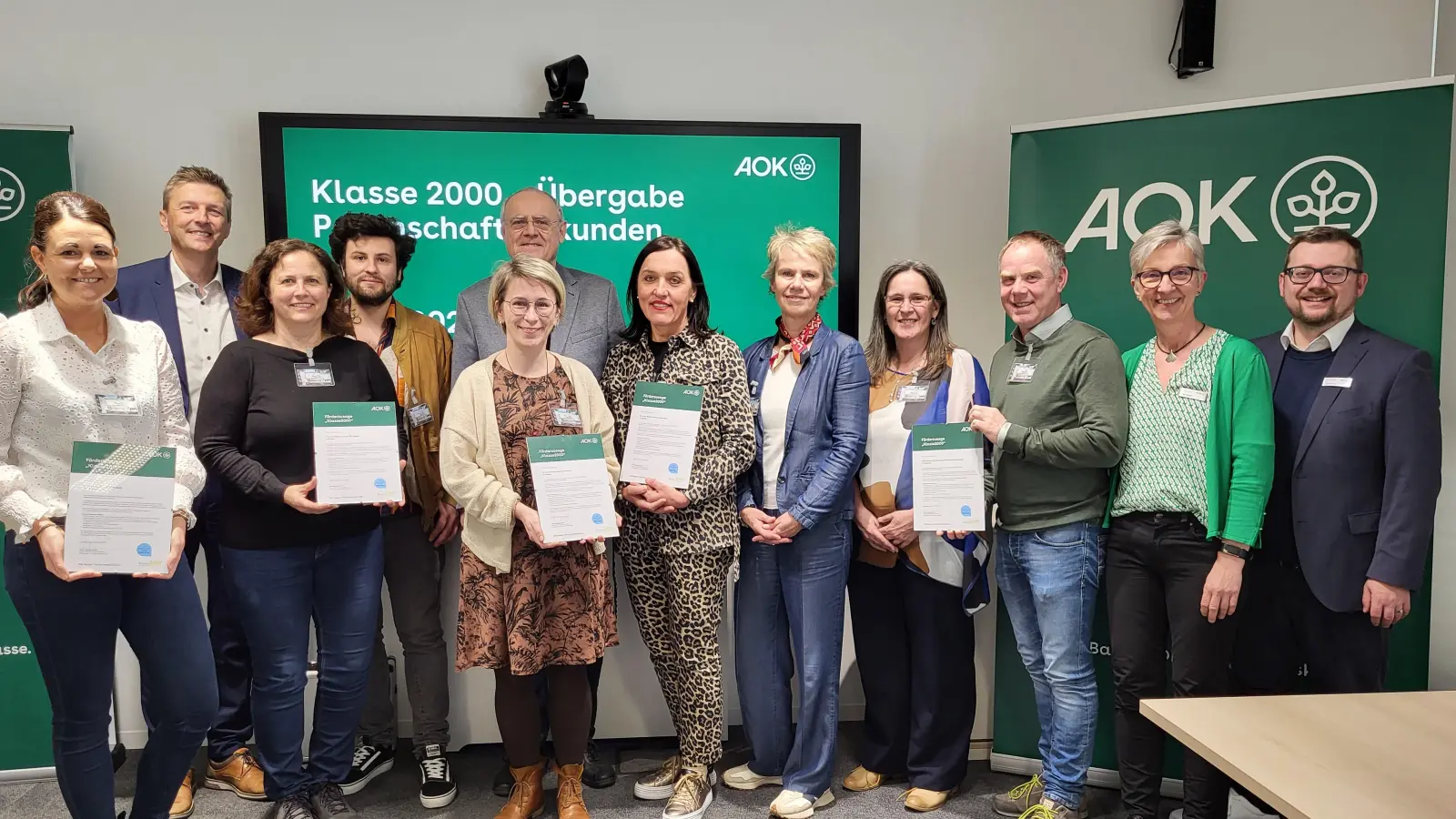 Direktor Jürgen Spickenreuther (hinten links) und AOK-Beiratsvorsitzender Lothar-Höher (hinten Mitte) mit Schulamtsdirektorin Christine Söllner (Mitte mit Halstuch) sowie die Vertreter der Grundschule Altenstadt, Gerhardinger- Rehbühl- St. Felix und Stötznerschule (mit Urkunden) mit Gesundheitsfachkraft Ulrike Rauch und Teamleiter Alwin Heim (rechts) (Bild: Maria Möller)