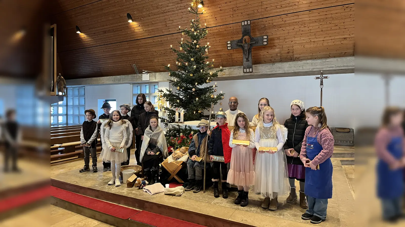 Die mitwirkenden Kinder beim Krippenspiel, vor dem Altar, mit Ruhestandspfarrer Dr. Joseph Madathiparampil. (Bild: Marion Baumer)