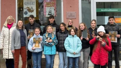 Die am Projekt beteiligten Schülerinnen und Schüler präsentieren gemeinsam mit der Zweiten Realschulkonrektorin Sandra Hering das entstandene Weihnachtsbuch vor dem „Bücherladen“ Kemnath, in dem das Werk nun auch in mehreren Fremdsprachen erhältlich ist. (Bild: Maria Busch)