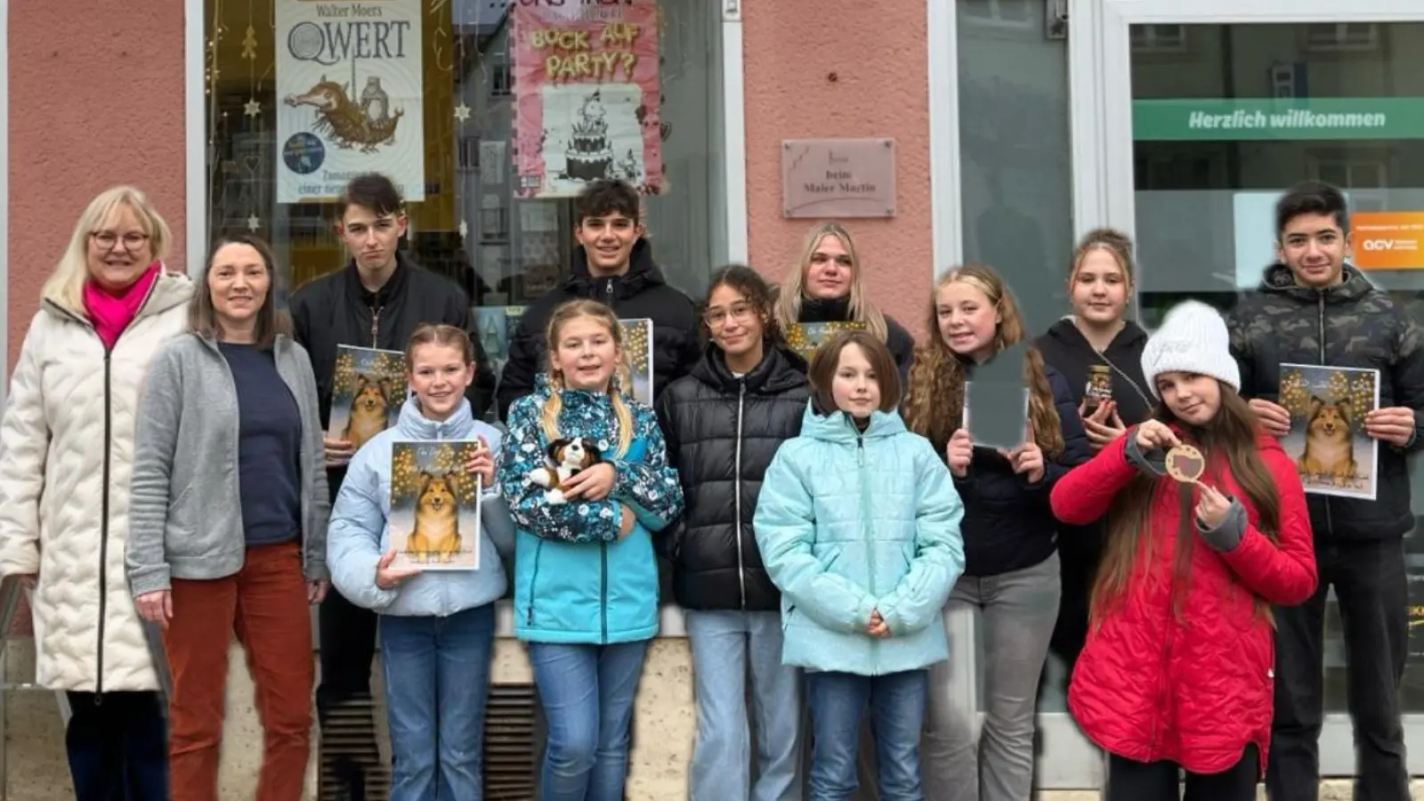 Die am Projekt beteiligten Schülerinnen und Schüler präsentieren gemeinsam mit der Zweiten Realschulkonrektorin Sandra Hering das entstandene Weihnachtsbuch vor dem „Bücherladen“ Kemnath, in dem das Werk nun auch in mehreren Fremdsprachen erhältlich ist. (Bild: Maria Busch)