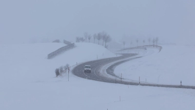 Ein Auto fährt im Schneetreiben auf einer Landstraße. (Bild: Karl-Josef Hildenbrand/dpa)