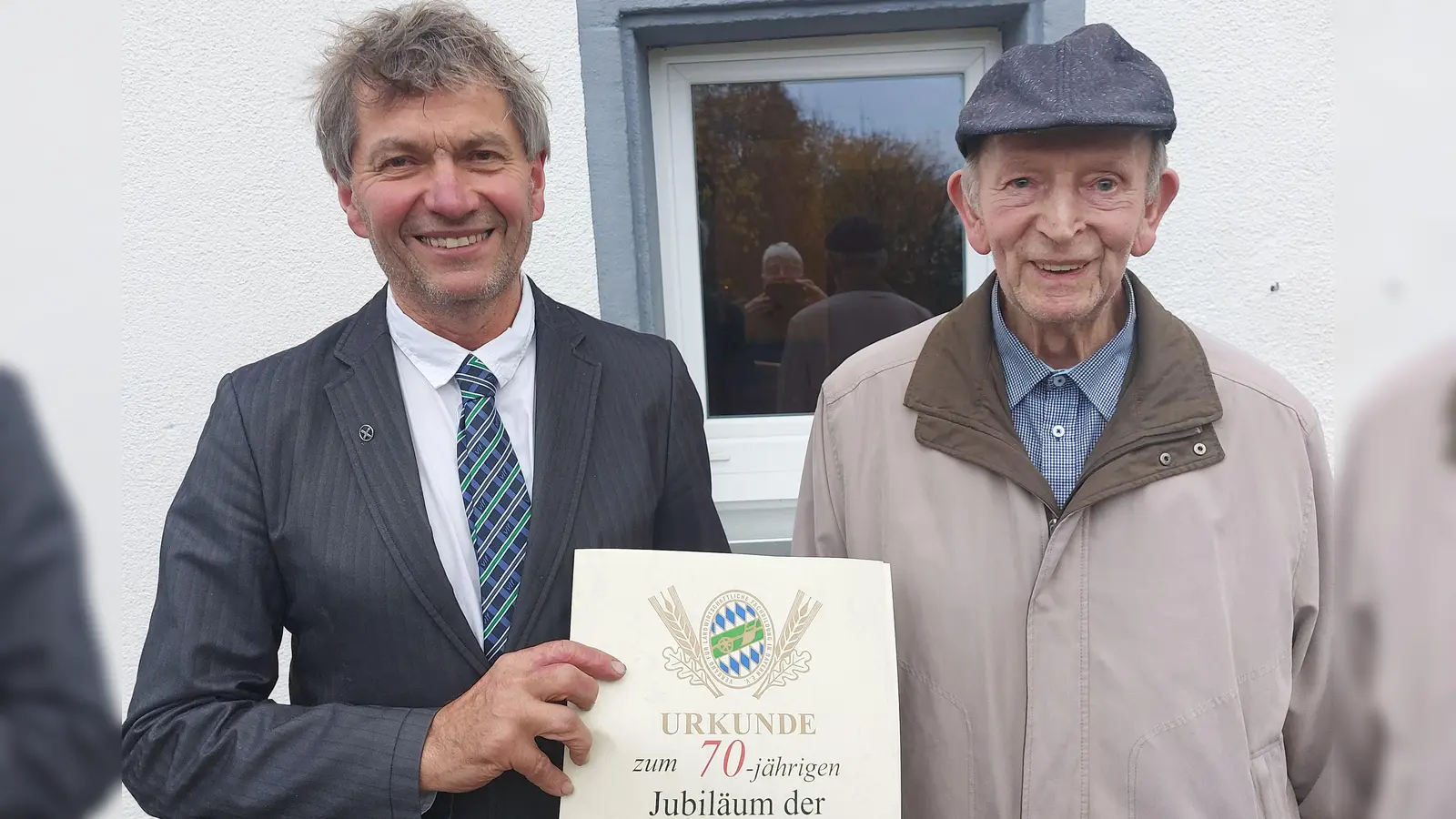 Konrad Janner aus Napfberg bei Erbendorf ist seit 70 Jahren Mitglied im Verband für landwirtschaftliche Fachbildung (vlf) im Landkreis Tirschenreuth. Dazu gratulierte der stellvertretende Vorsitzende Hans Scherm mit einer Ehrenurkunde und einem Landkreiskorb (Bild: Wolfgang Wenisch)
